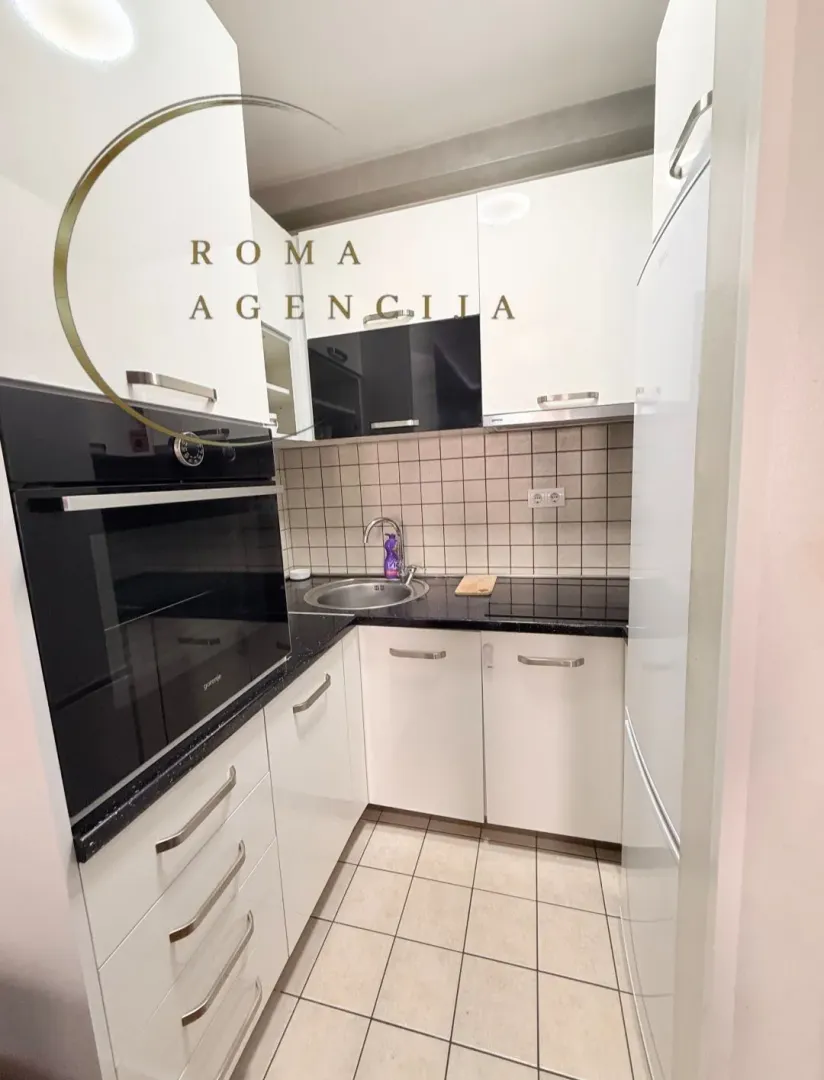 Smaller modern kitchen with white cabinets and a built-in oven.