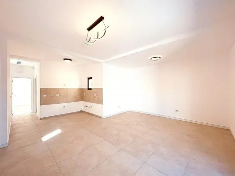 Empty living room with ceramic floor tiles and a prepared space for a kitchen. - image 4