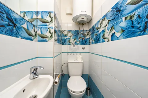 Smaller bathroom with a toilet, washbasin, and wall-mounted water heater. - image 9