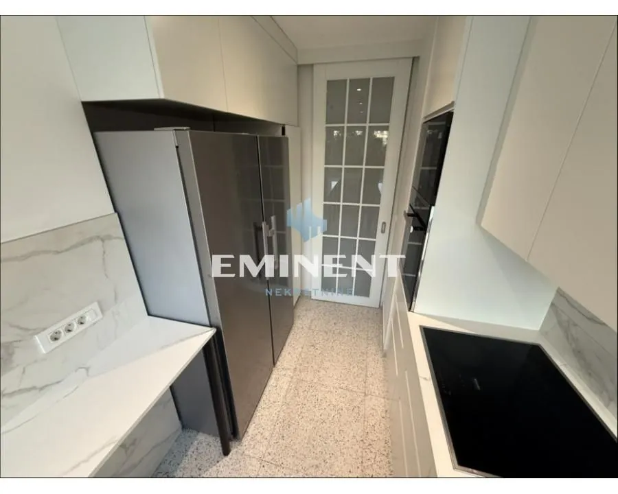 Modern white kitchen with built-in appliances and a large refrigerator.