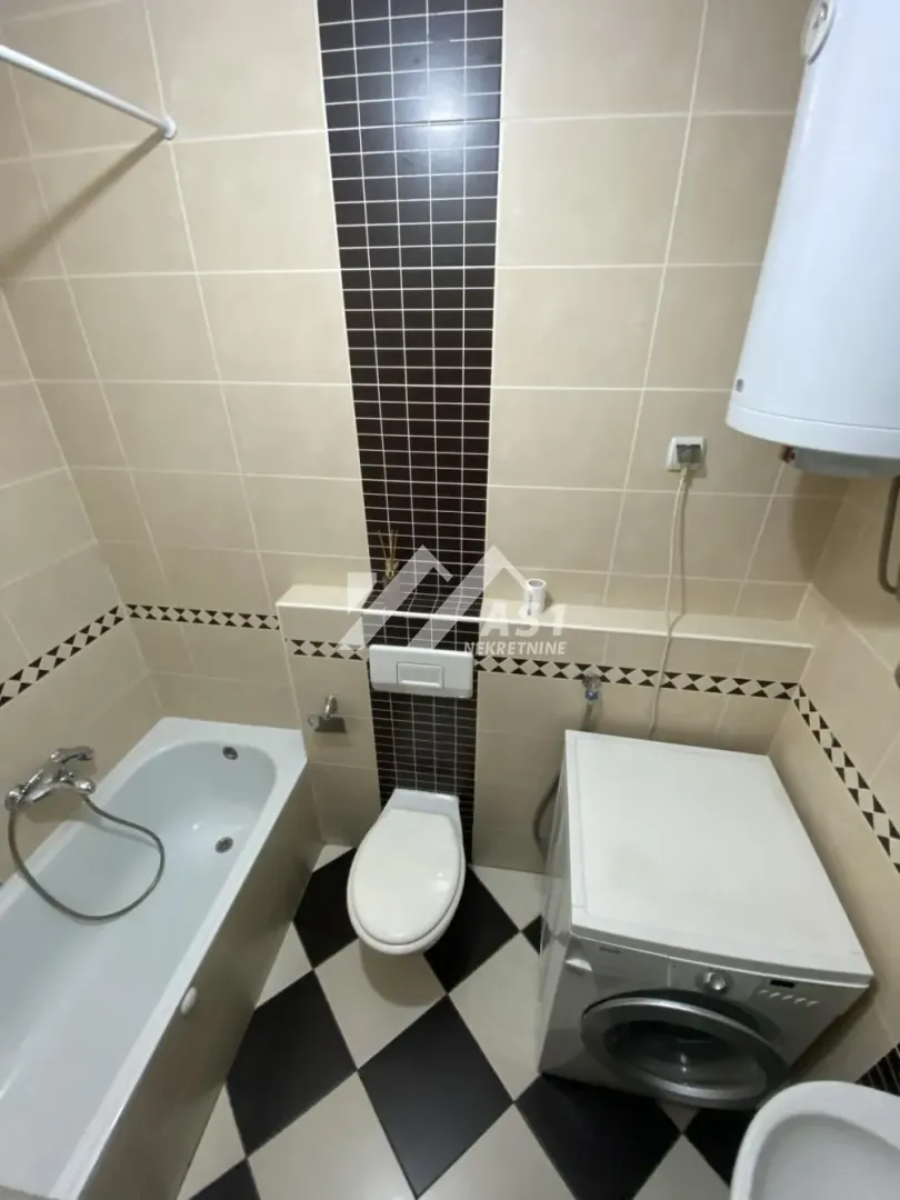 Kupatilo opremljeno kadom, wc šoljom i veš mašinom.