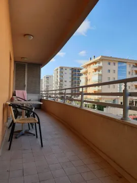 Long terrace with a table, chairs, and view of surrounding buildings. - image 4