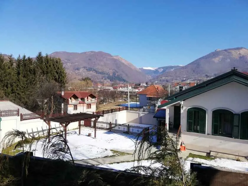 Pogled na dvorište kuće i okolne planine sa snijegom.