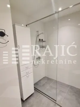 Modern bathroom with walk-in shower and white furniture. - image 8