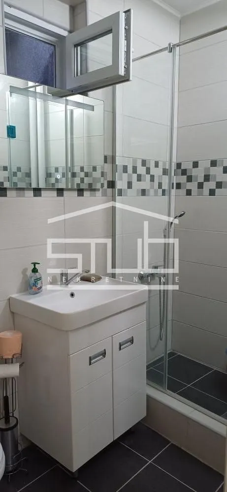 Compact bathroom with a vanity sink, mirror, and a shower cabin.