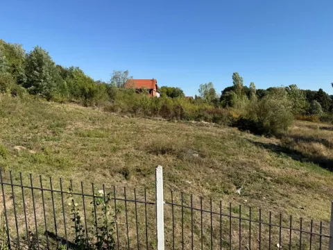 Pogled na plac sa travnatom površinom i ogradom u prvom planu. - image 4