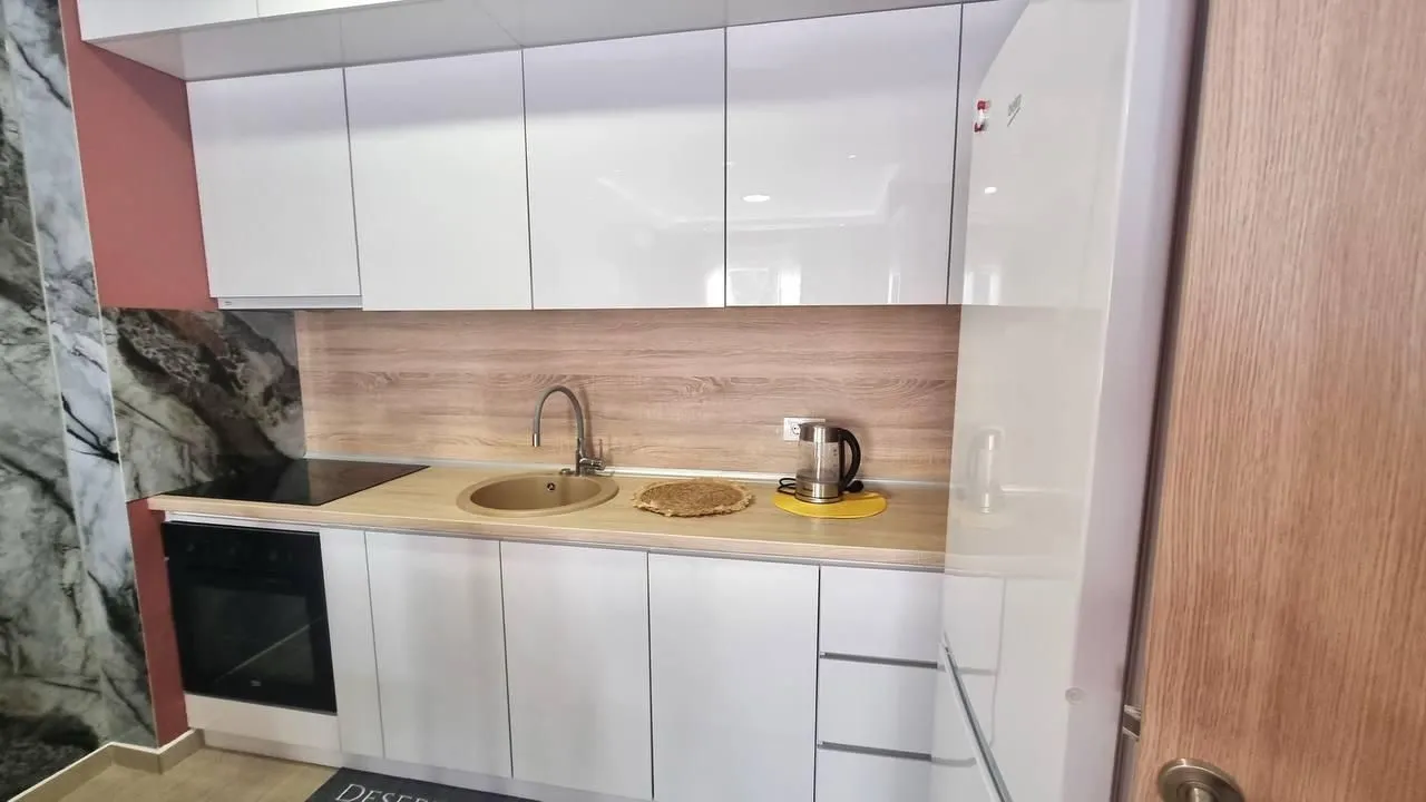 Modern kitchen with white cabinets and a wooden countertop.