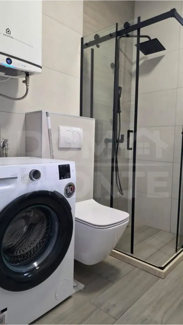 Moderno opremljeno kupatilo sa tuš kabinom, wc šoljom i veš mašinom.