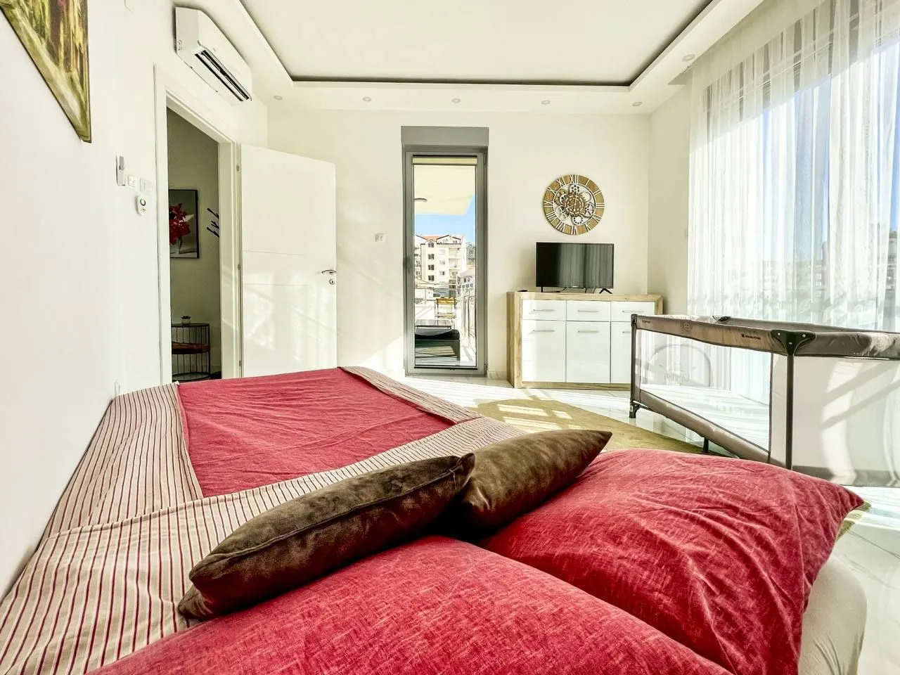 Bright bedroom with a large bed, dresser, and balcony access.