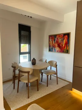 Dining area with a round table, four chairs, and a painting on the wall. - image 9