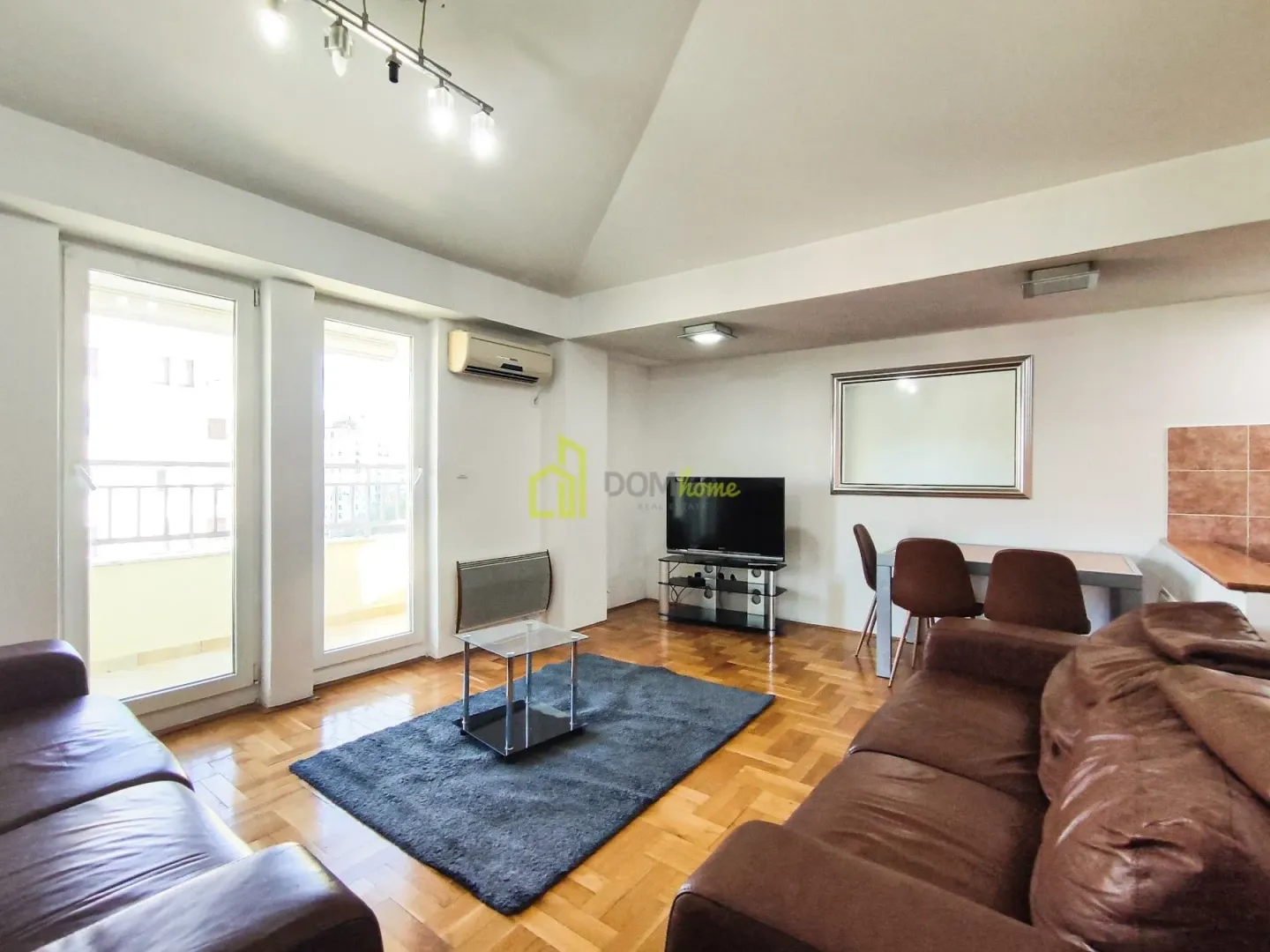 Spacious living room with sofa set, parquet flooring, and access to the terrace.