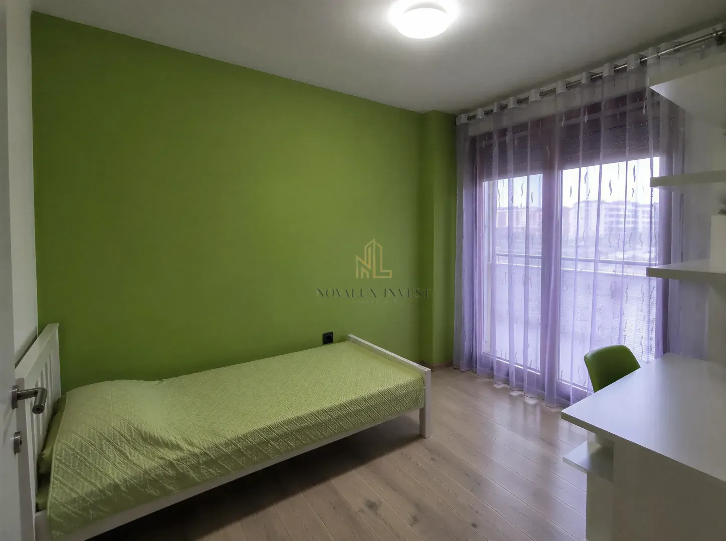 Children's bedroom with a bed, desk, and balcony doors.