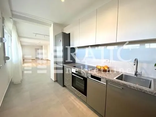 View of a modern kitchen with built-in appliances and a dining area in the background.