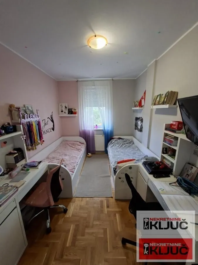 Dečja soba sa dva kreveta i radnim stolovima.