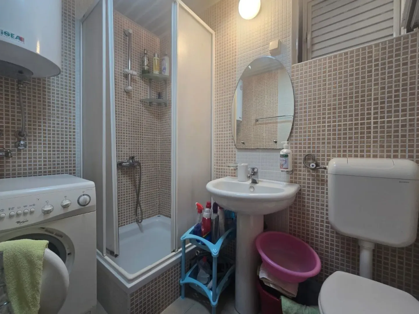 Small bathroom with a shower cabin, washbasin, and washing machine.