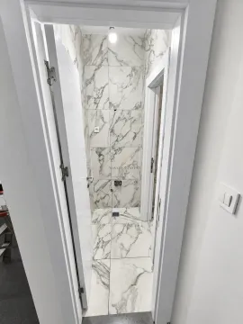 A view of a bathroom under construction lined with marble tiles. - image 4