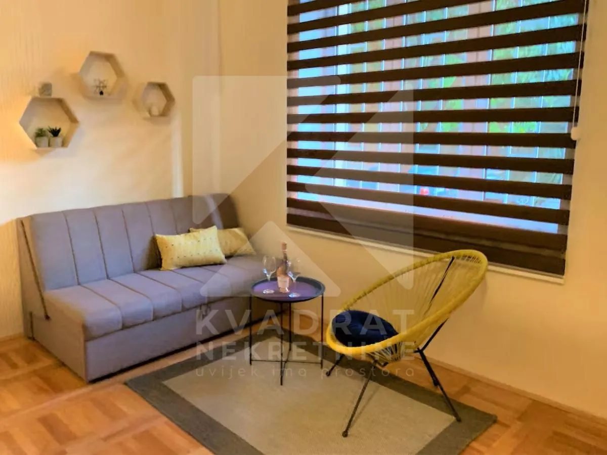 Living room with a grey sofa, yellow armchair, and a small table by the window.