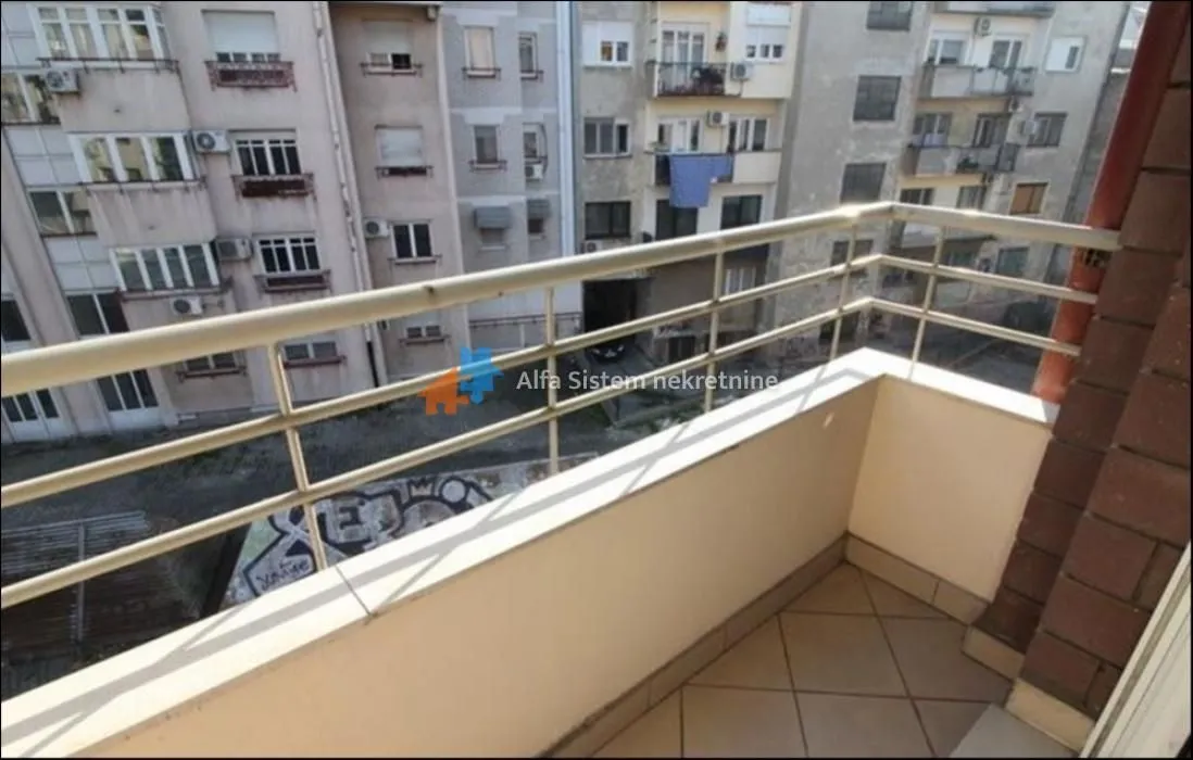 Small tiled balcony with a metal railing and a view of neighboring buildings.