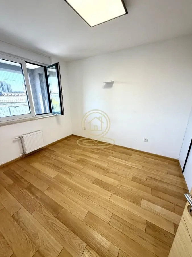 Empty room with hardwood flooring and a window.