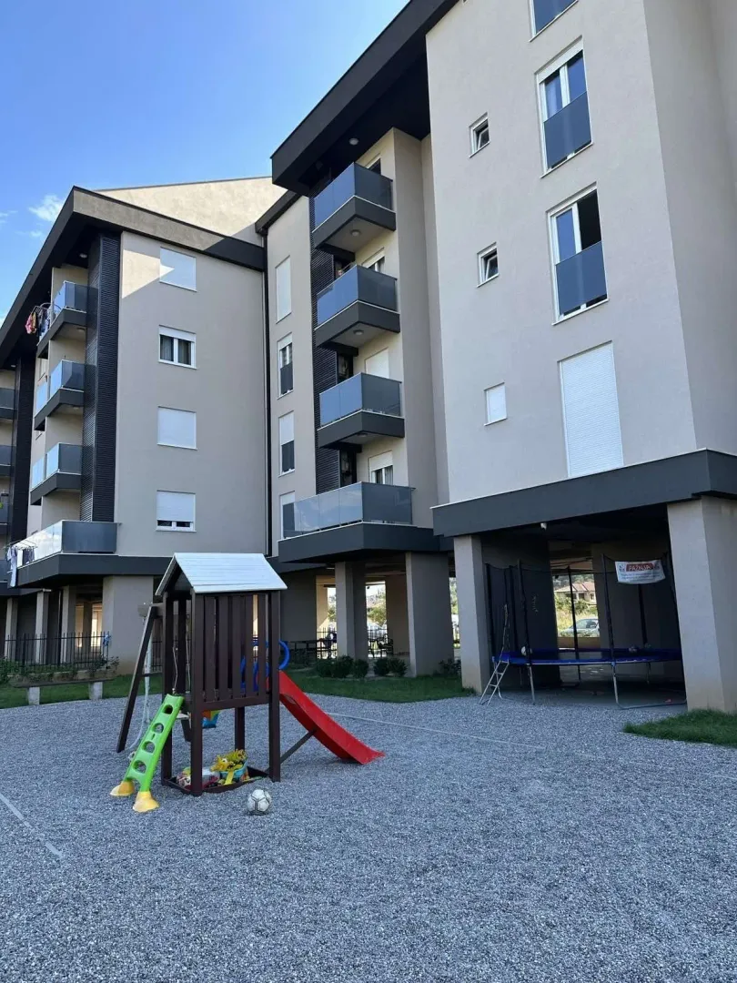 Exterior of a modern residential building with a children's playground in the yard.