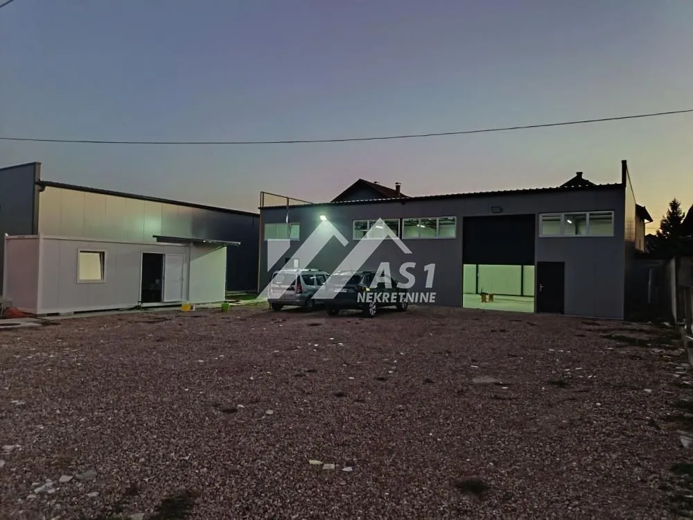 Exterior view of the commercial building with a spacious courtyard and parked vehicles.