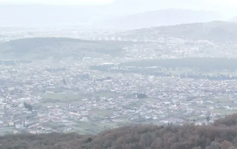 Panoramski pogled na naselje i okolna brda pod maglom. - image 2
