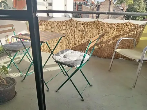 Furnished balcony with a table, chairs, and a view of surrounding buildings. - image 2