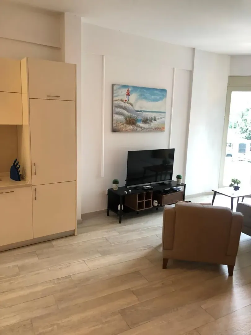 Living room with a seating area and TV connected to kitchen units.