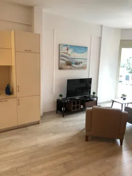 Living room with a seating area and TV connected to kitchen units. - image 14
