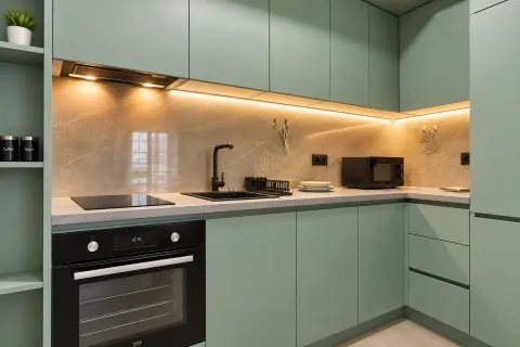 View of a modern kitchen with green cabinets and built-in appliances. - image 5