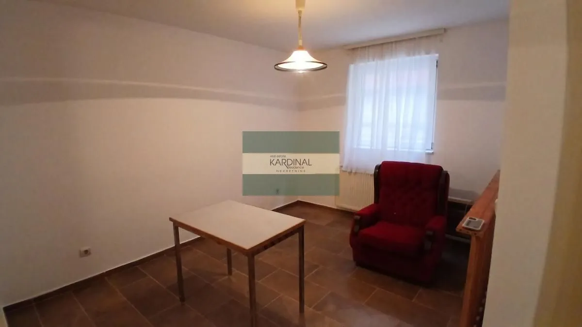 Dnevna soba sa stolom i crvenom foteljom.