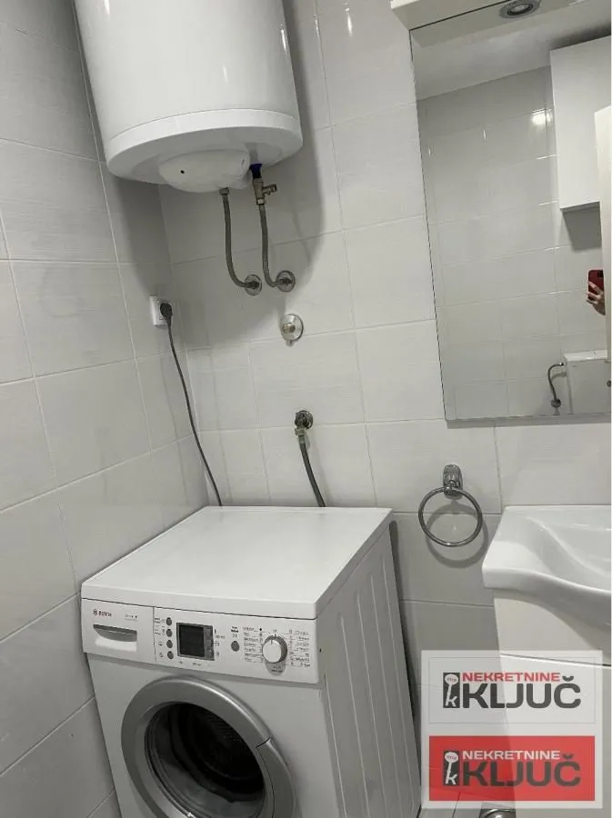 Manje kupatilo sa veš mašinom, umivaonikom i bojlerom.