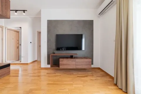 Moderan dnevni boravak sa drvenim podom, televizorom na zidu i klima uređajem. - image 9