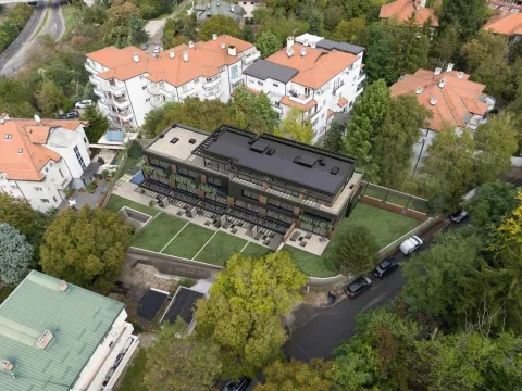 Pogled iz vazduha na modernu zgradu i okolno naselje sa zelenilom. - image 6