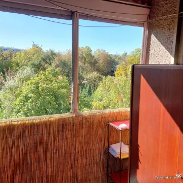 Manji zatvoreni balkon sa pogledom na zelene krošnje drveća. - image 8