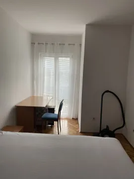 A simple bedroom with a desk, chair, and access to a balcony. - image 6