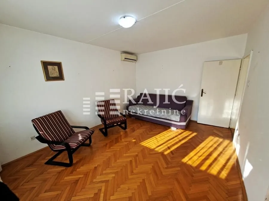 Living room with sofa, armchairs, and parquet flooring.
