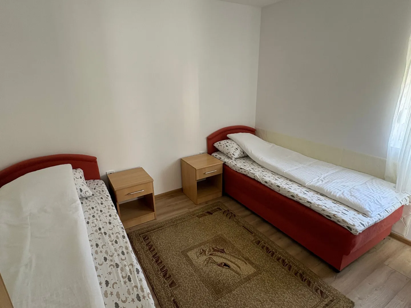 Spavaća soba sa dva kreveta i noćnim stočićima.