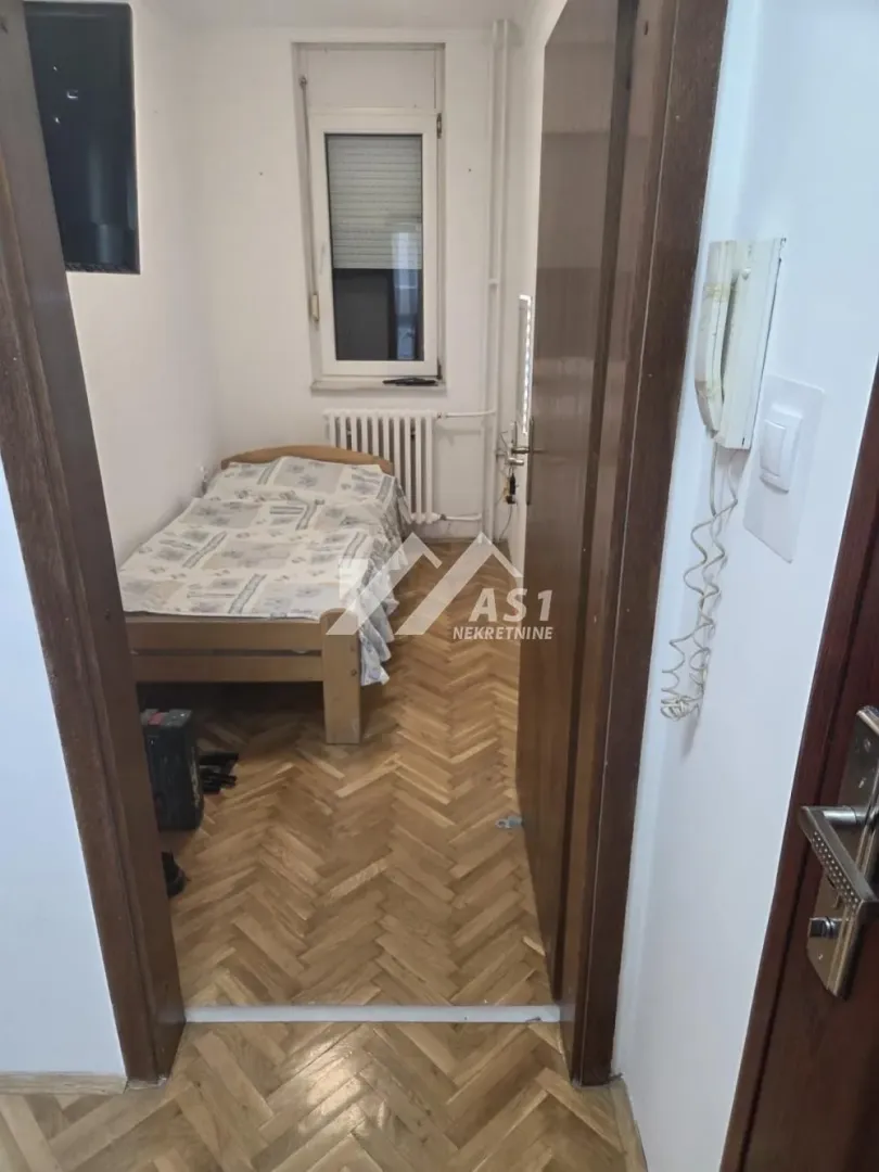 Pogled iz hodnika na spavaću sobu sa krevetom i parketom.
