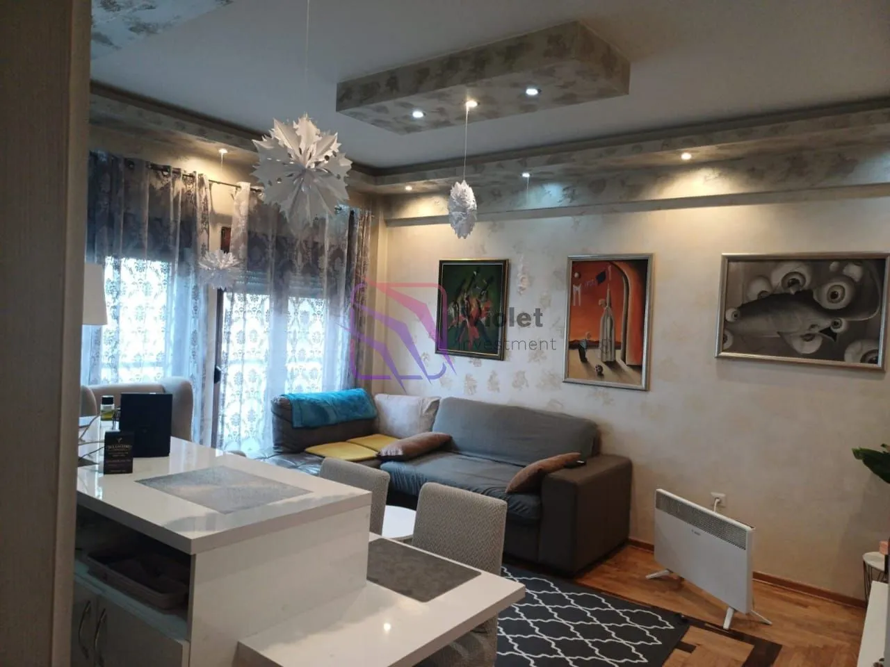 Living room with sofa, dining area and decorative paintings on the wall.