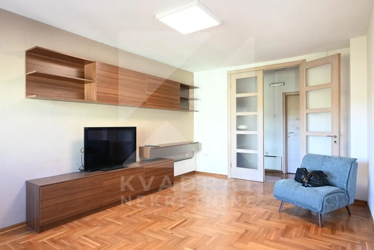 Living room with wooden furniture, a television, and parquet flooring.