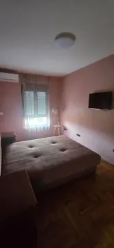 Spavaća soba sa bračnim krevetom, televizorom i prozorom. - image 4