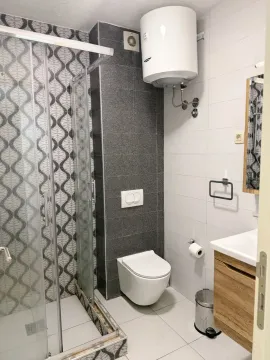 Modern bathroom equipped with a shower cabin, toilet, and vanity sink. - image 10