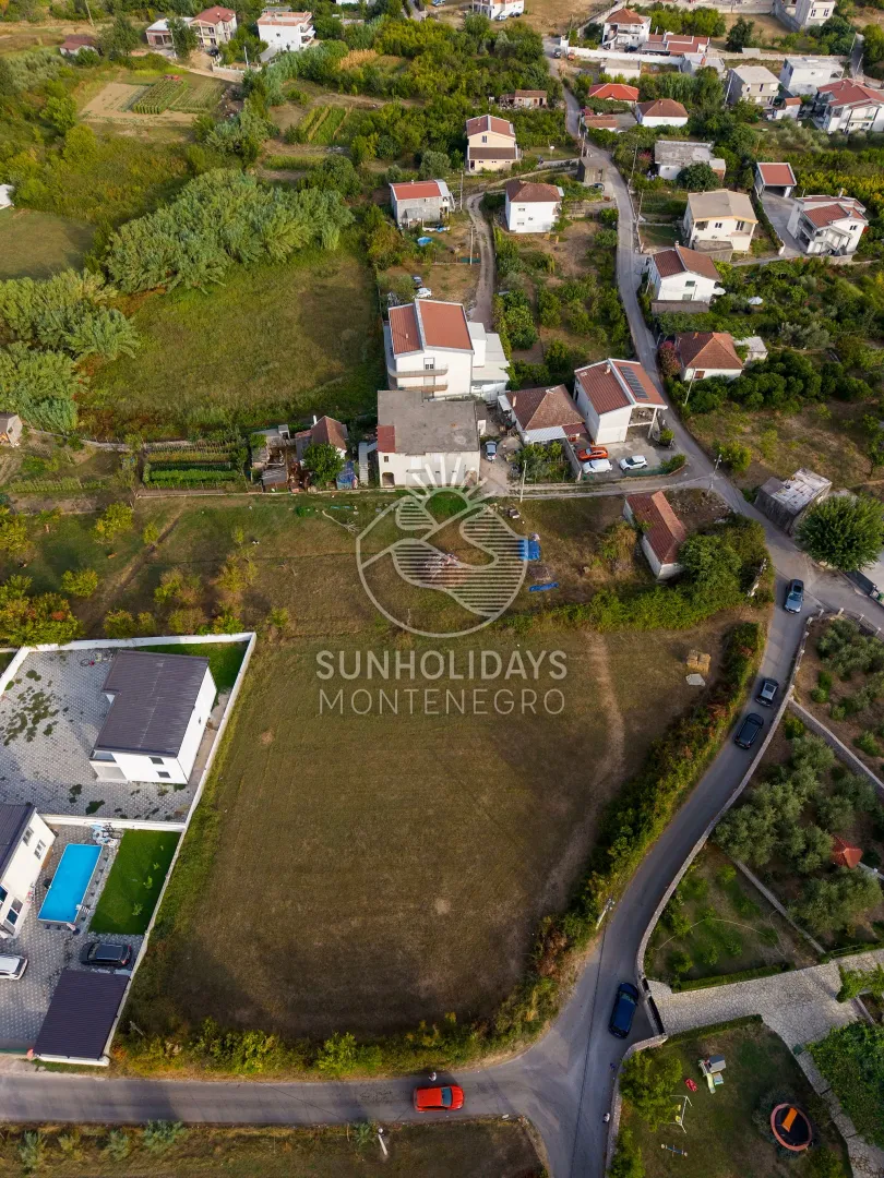 Pogled iz vazduha na plac i okolno naselje sa kućama.