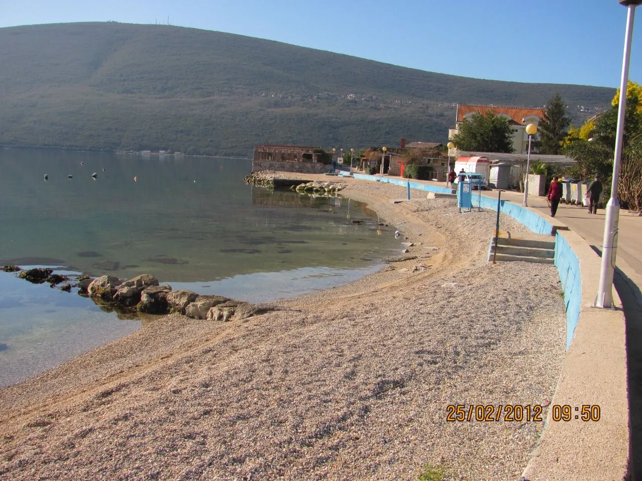 Pogled na šetalište, plažu i obalu mora sa planinom u pozadini.