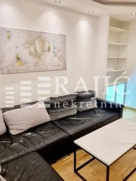 Living room with a sofa, coffee table, and built-in shelves. - image 7