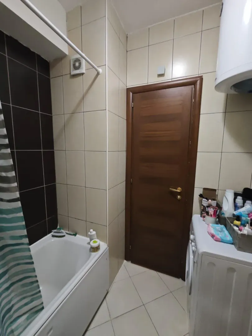 Manje kupatilo sa kadom, drvenim vratima i veš mašinom.