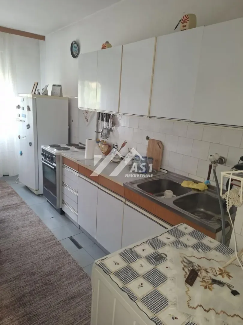 Starija kuhinja sa belim elementima i belom tehnikom.