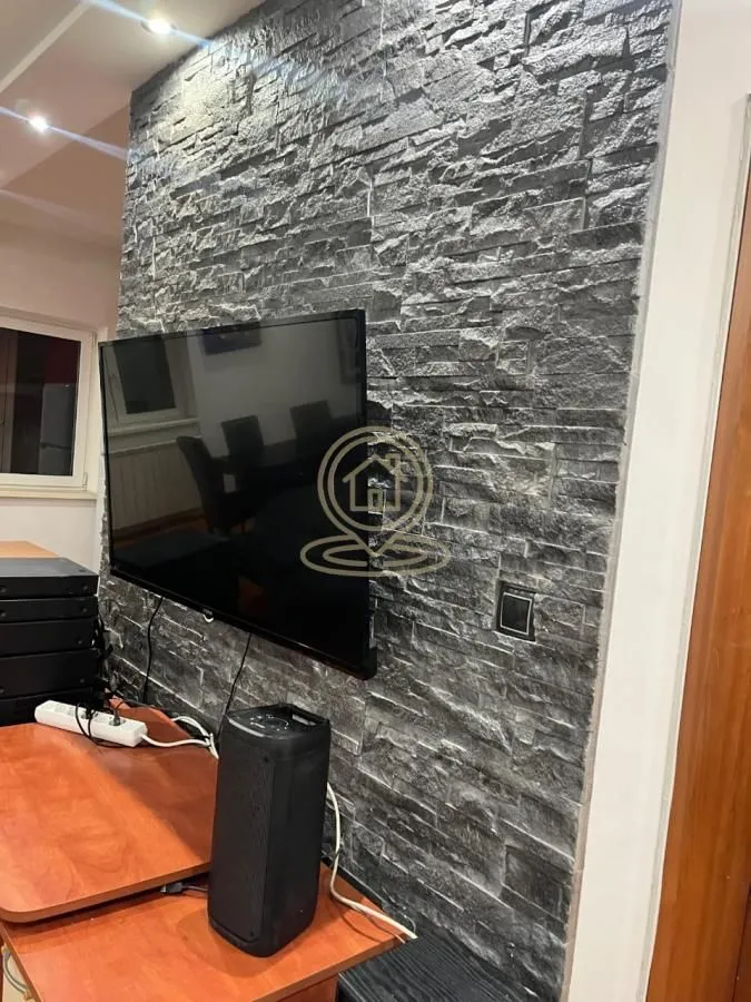 Living room with a decorative stone-clad wall and a mounted television.
