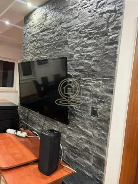 Living room with a decorative stone-clad wall and a mounted television. - image 6